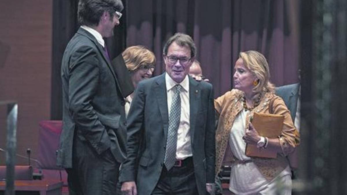 Artur Mas, junto a su mujer y su jefe de prensa, se dirige al hemiciclo, ayer en el Parlament.