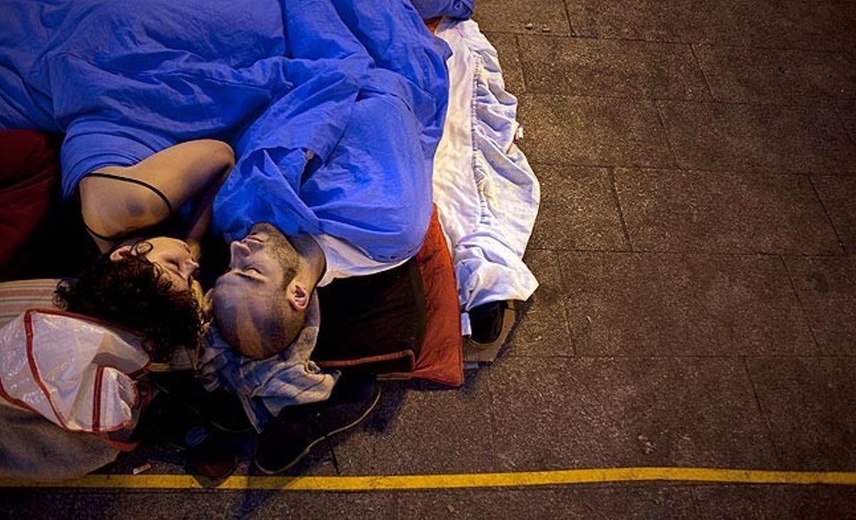 Una parella dorm aquest dimarts en l’acampada de Puerta del Sol, a Madrid.
