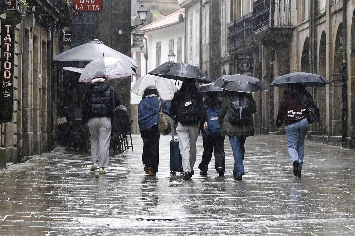 Varios compostelanos se cobijan bajo el paraguas