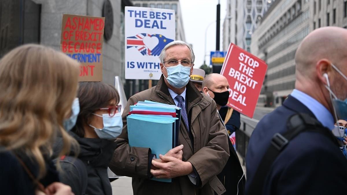 Manifestantes anti-brexit muestran pancartas al paso del negociador de la UE, Michel Barnier, este lunes en Londres.