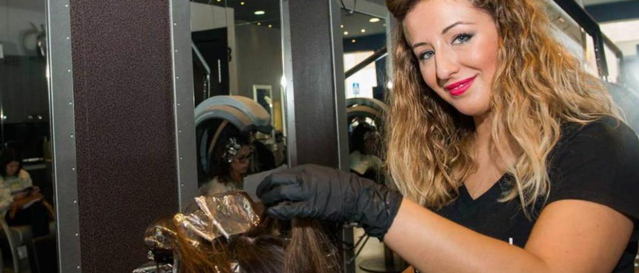 María Montes pone mechas a una clienta en la peluquería.