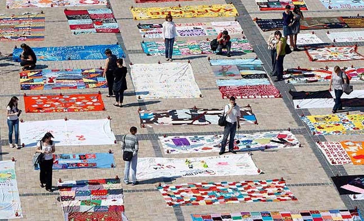 Un grup de gent observa alfombres creades per persones seropositives durant un acte celebrat a Kíev.