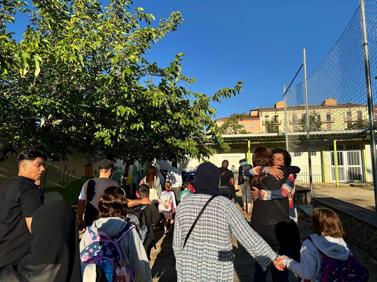 Entrada d'alumnes al centre educatiu on es veuen els barracons de fons