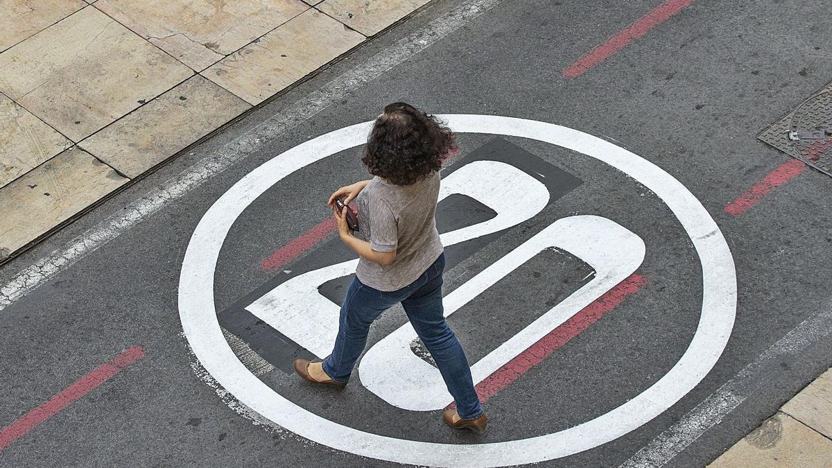 Una mujer camina sobre la nueva señal de limitación a 20 kilómetros por hora pintada en la plaza del Ayuntamiento este miércoles | ALEX DOMÍNGUEZ