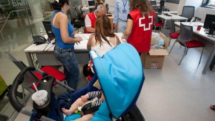 Miembros de Cruz Roja de Alicante, entregando productos infantiles este verano.