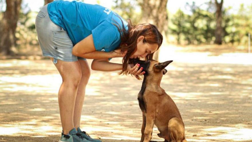 Una educadora canina fent un petó a un gos.