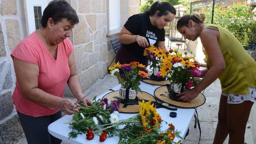 Belén Guimeráns (primer plano) con su hija Elena (al fondo) y Susana Barredo confeccionan sombreros de flores. // Gonzalo Núñez