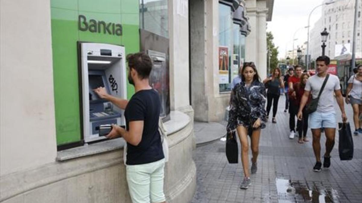 Un cliente saca dinero de un cajero de Bankia en Barcelona.