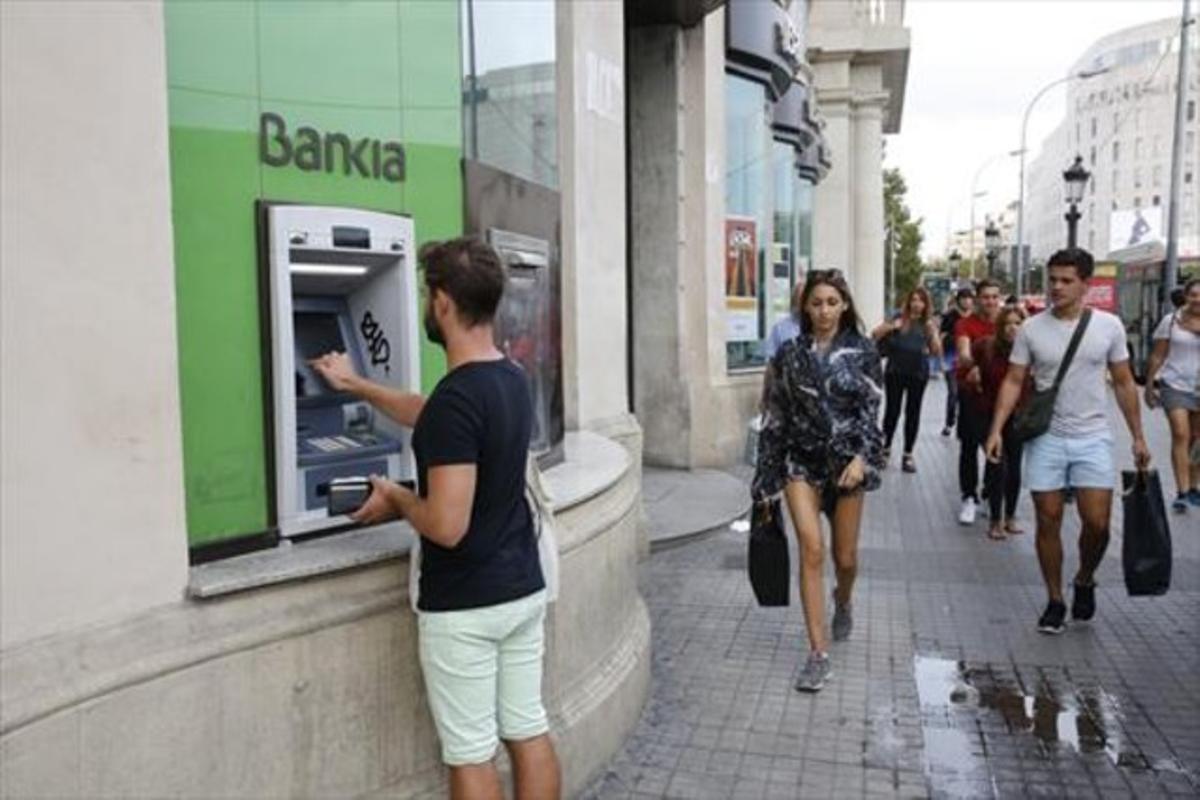 Un client treu diners d’un caixer de Bankia a Barcelona.