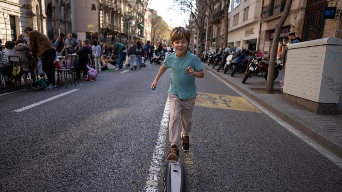 Un niño corre por la calzada de València, frente a la Escola de l'Eixample.