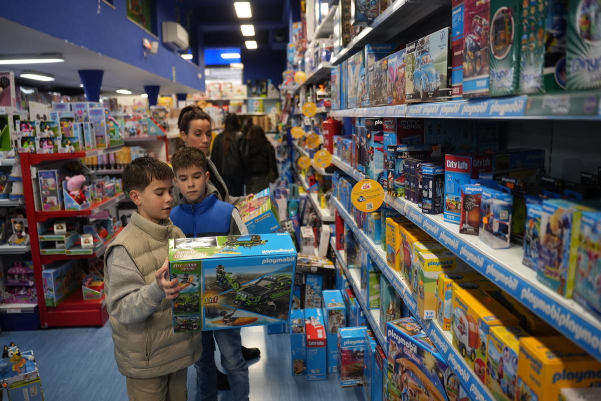 Niños coge una caja de Playmobil en una juguetería.