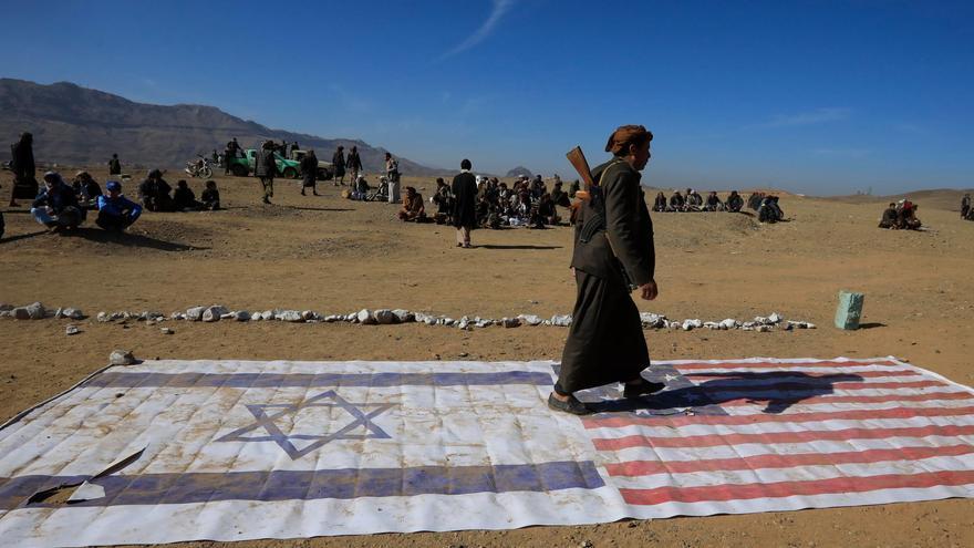 Un integrante de una tribu leal a los hutíes camina encima de las banderas de Israel y Estados Unidos durante un encuentro para combatientes recientemente reclutados el 22 de enero en las afueras de Saná. EFE/YAHYA ARHAB