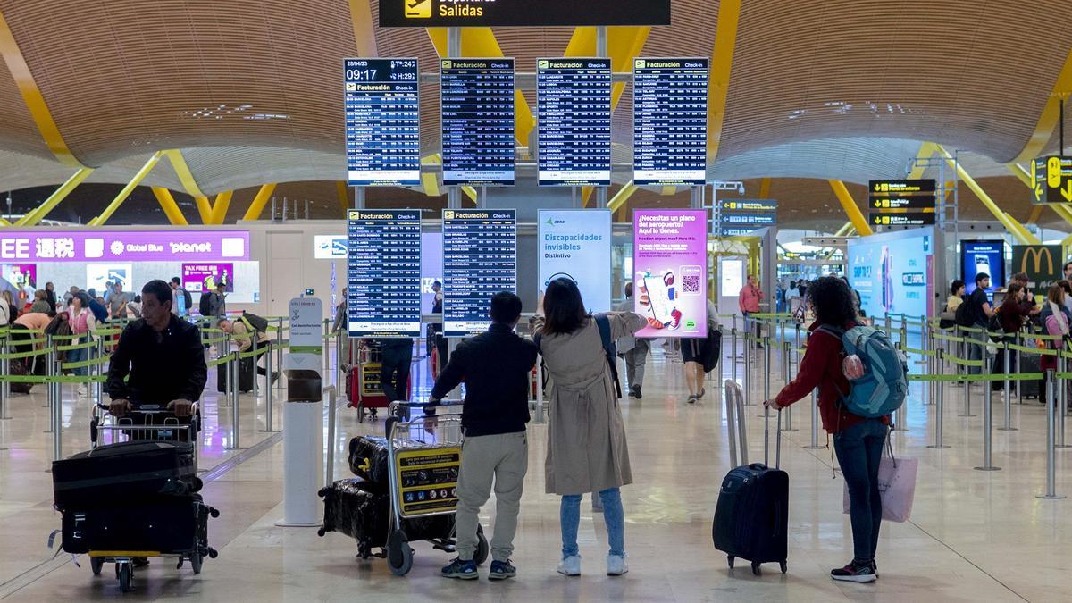 Un grupo de personas frente al panel del orden de vuelos en la terminal T4 del aeropuerto de Adolfo Suárez-Madrid Barajas, a 28 de abril de 2023, en Madrid (España).