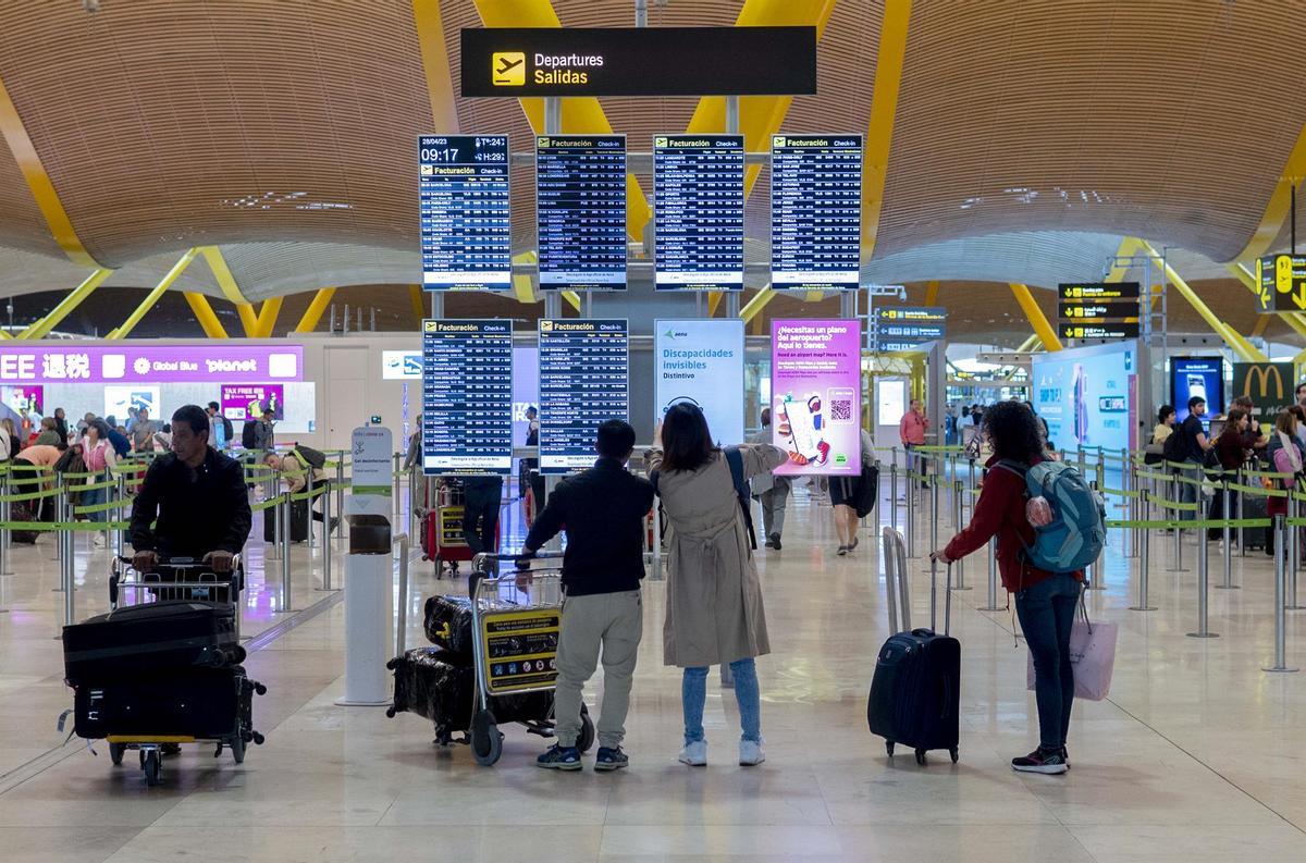 Un grupo de personas frente al panel del orden de vuelos en la terminal T4 del aeropuerto de Adolfo Suárez-Madrid Barajas, a 28 de abril de 2023, en Madrid (España).