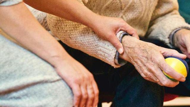 Una mujer da la mano a un hombre mayor |