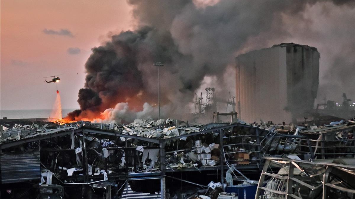 Un helicóptero apaga un incendio en el lugar de una terrible explosión en el puerto de Beirut, la capital del Líbano, el 4 de agosto de 2020