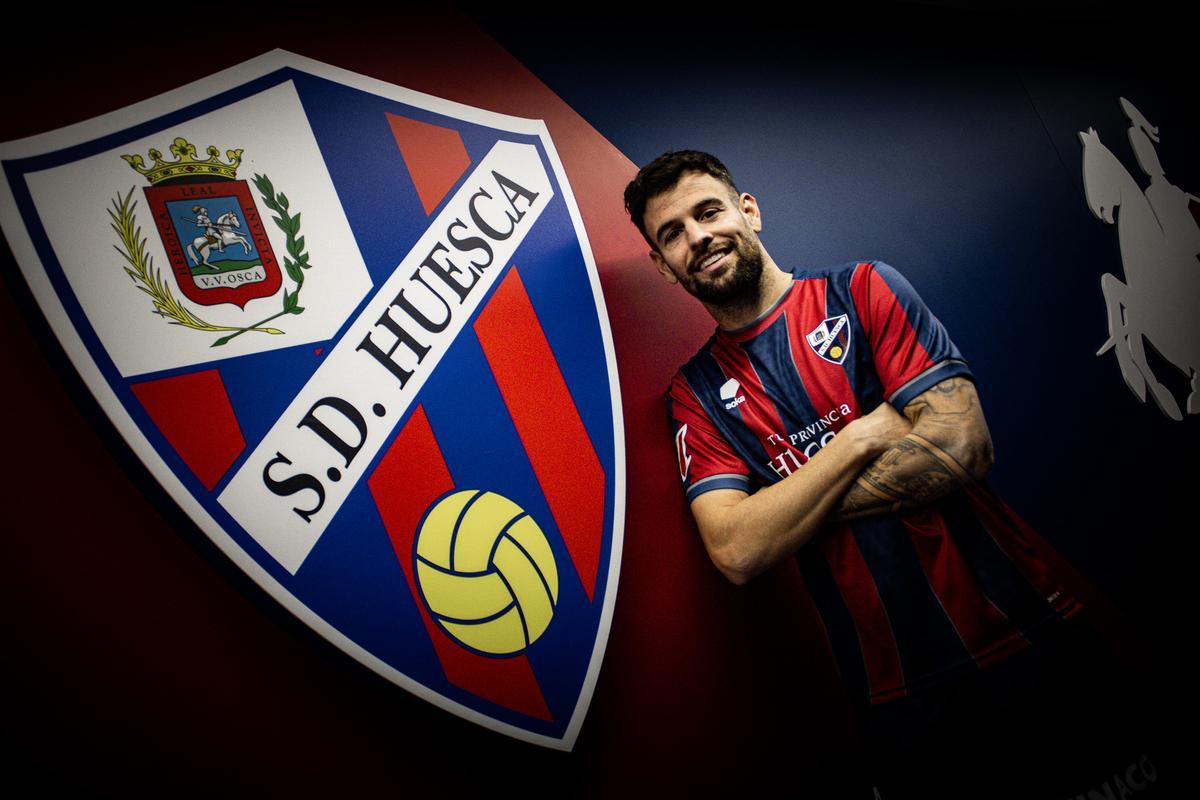 Moi Delgado, único fichaje del Huesca, posa junto al escudo oscense en su presentación.