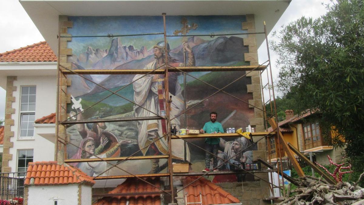 Raúl Prieto, subido a los andamios, rematando su mural de Don Pelayo. | J. M. C.