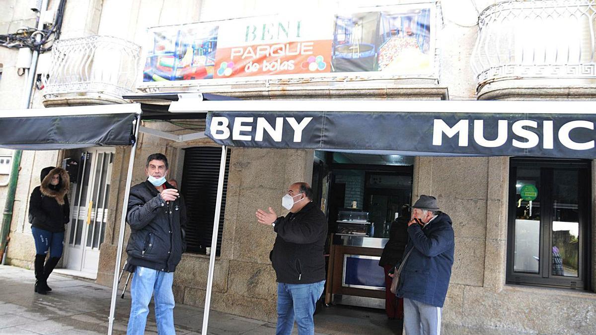 Vecinos de Bueu esperando ayer para recoger un café para llevar en un local. |