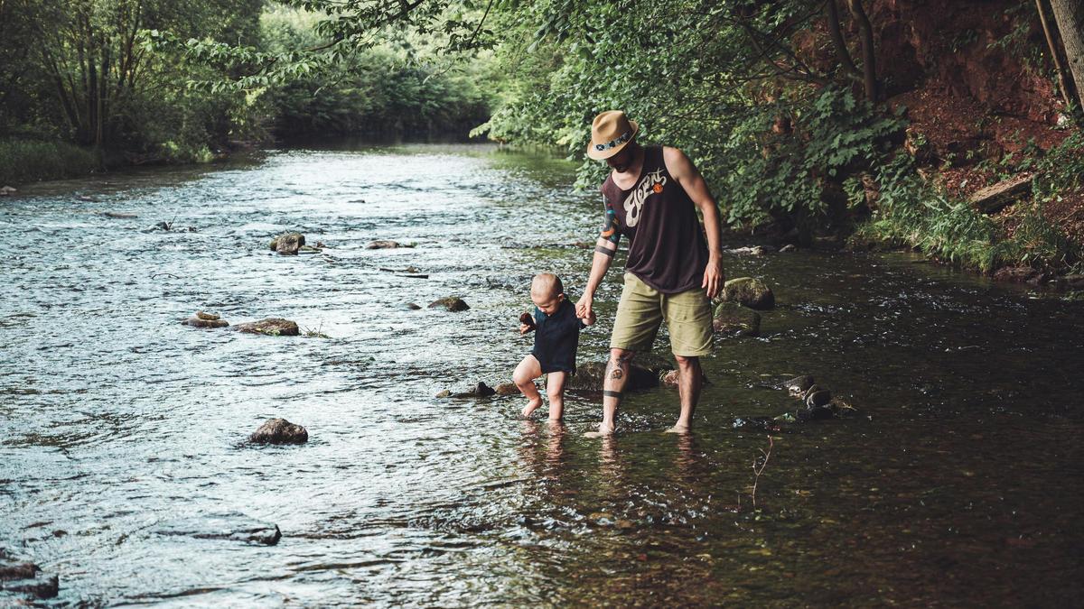 Un padre camina con su bebé por el río