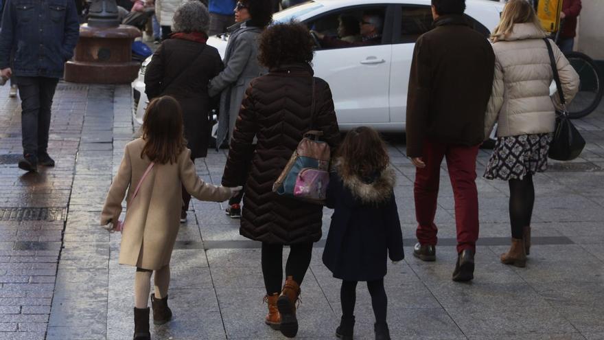 Una madre pasea por Zaragoza de la mano de sus dos hijas, en la calle Alfonso I de la capital aragonesa, este puente.