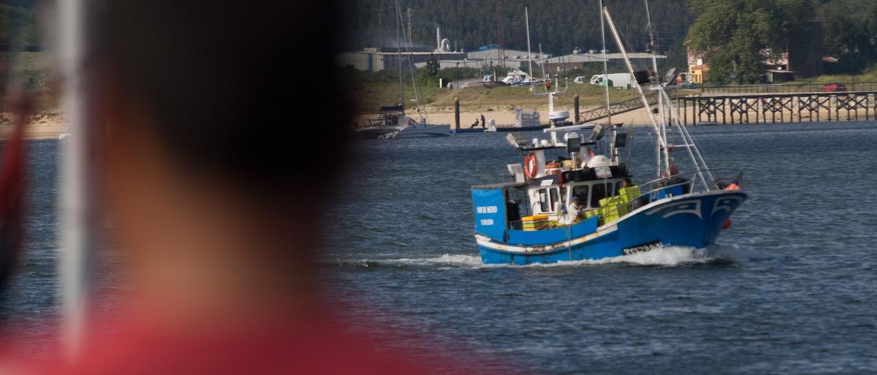 Un hombre observa la llegada a puerto de un barco pesquero.