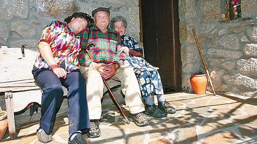 Elvira Martínez, a la izquierda, sentada al lado de sus padres en el patio de su casa en Casal do Regueiro, en Ramirás (Ourense).