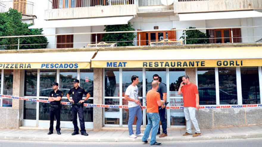 Investigadores del Grupo de Homicidios de la Policía Nacional junto a dos agentes que vigilan la entrada del restaurante donde se produjo el crimen.