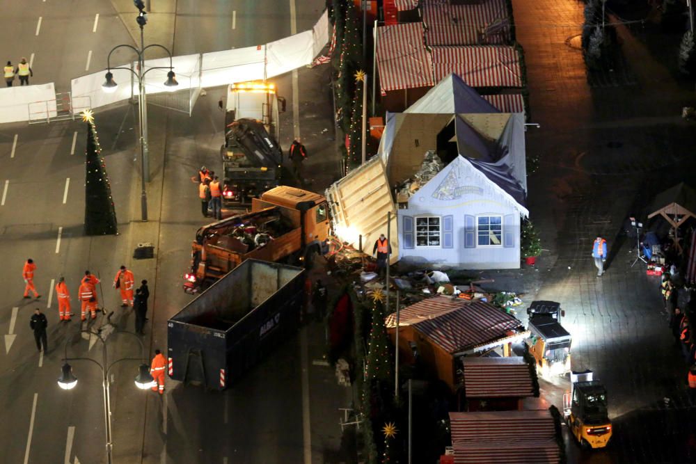 Varios trabajadores despejan el mercado navideño de Berlín tras la irrupción de un camión que arrolló a 12 personas.