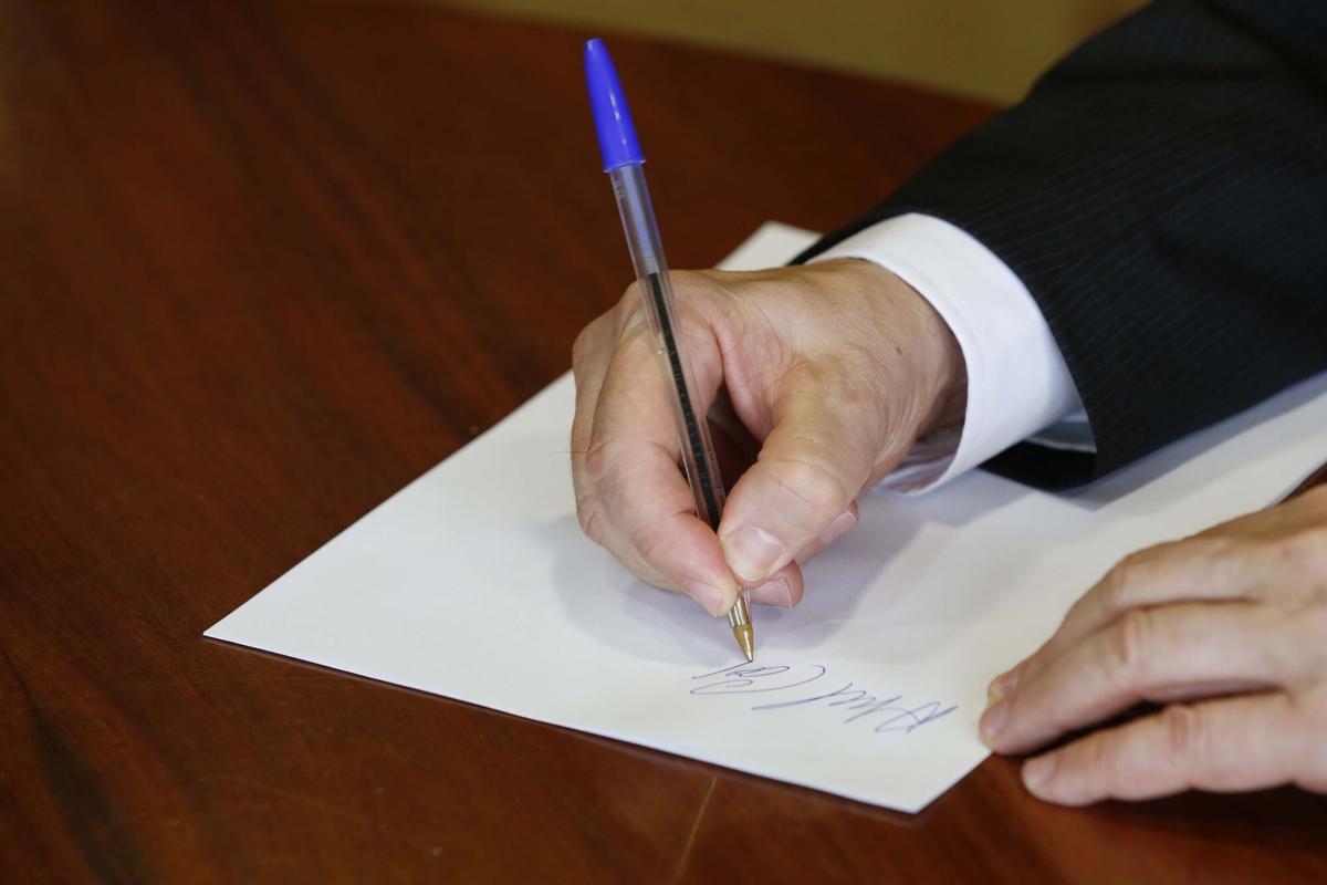 Un hombre firma un documento.