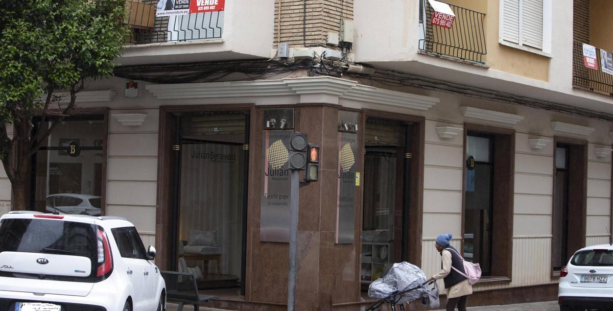 Una mujer con un carrito pasa por debajo de un piso a la venta en Xàtiva.