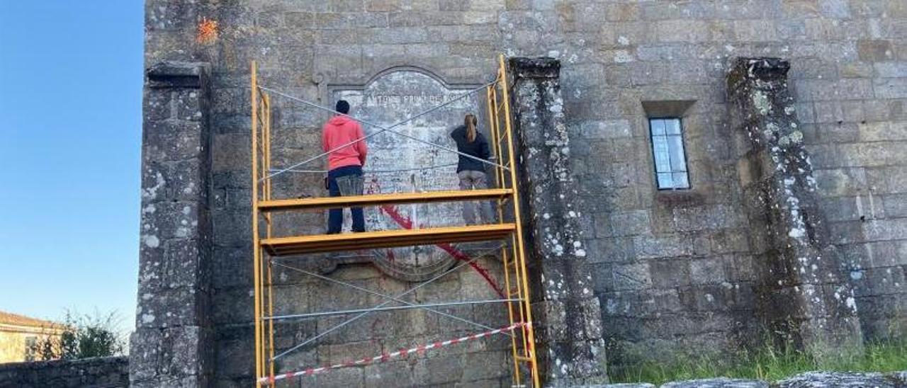 Los técnicos trabajando ayer sobre la plancha de hormigón en la lateral de la iglesia de Beluso. |   // FDV