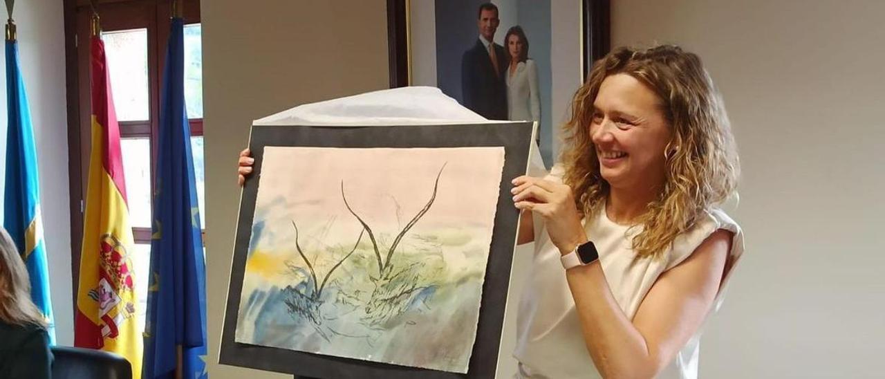 Natalia González muestra el grabado de la colección «Diluculum» de Ángel Cajal, obra inspirada en la cueva de la Peña de Candamo y obsequio del equipo de gobierno del PSOE. | S. Arias