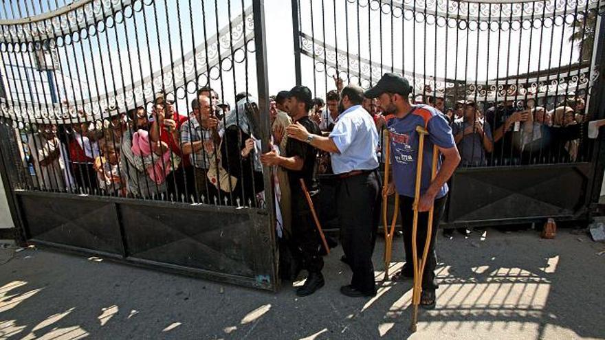 Varios palestinos esperan para cruzar por el paso de Rafah hacia Egipto, en el sur de la Franja de Gaza,. Este paso ha sido abierto esta mañana por Egipto y permanecerá así durante dos días más.