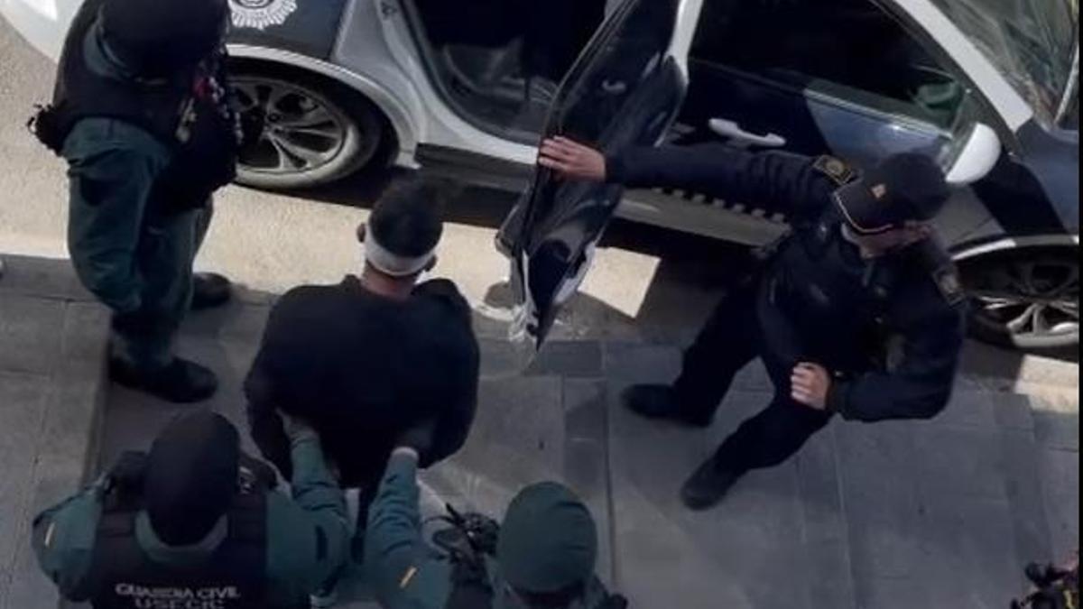 Los agentes introducen al detenido en un coche de la Policía Local.