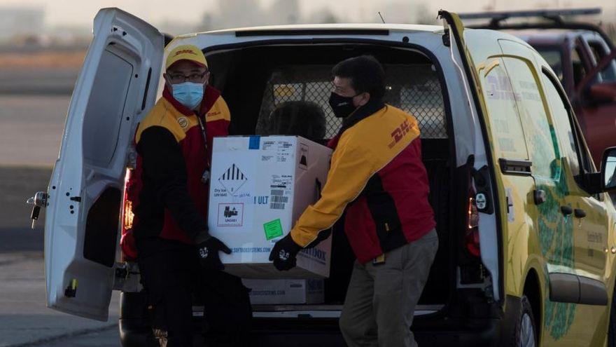 La vacuna de la covid de Pfizer llega a España: dos transportistas cargan una caja con las primeras dosis.