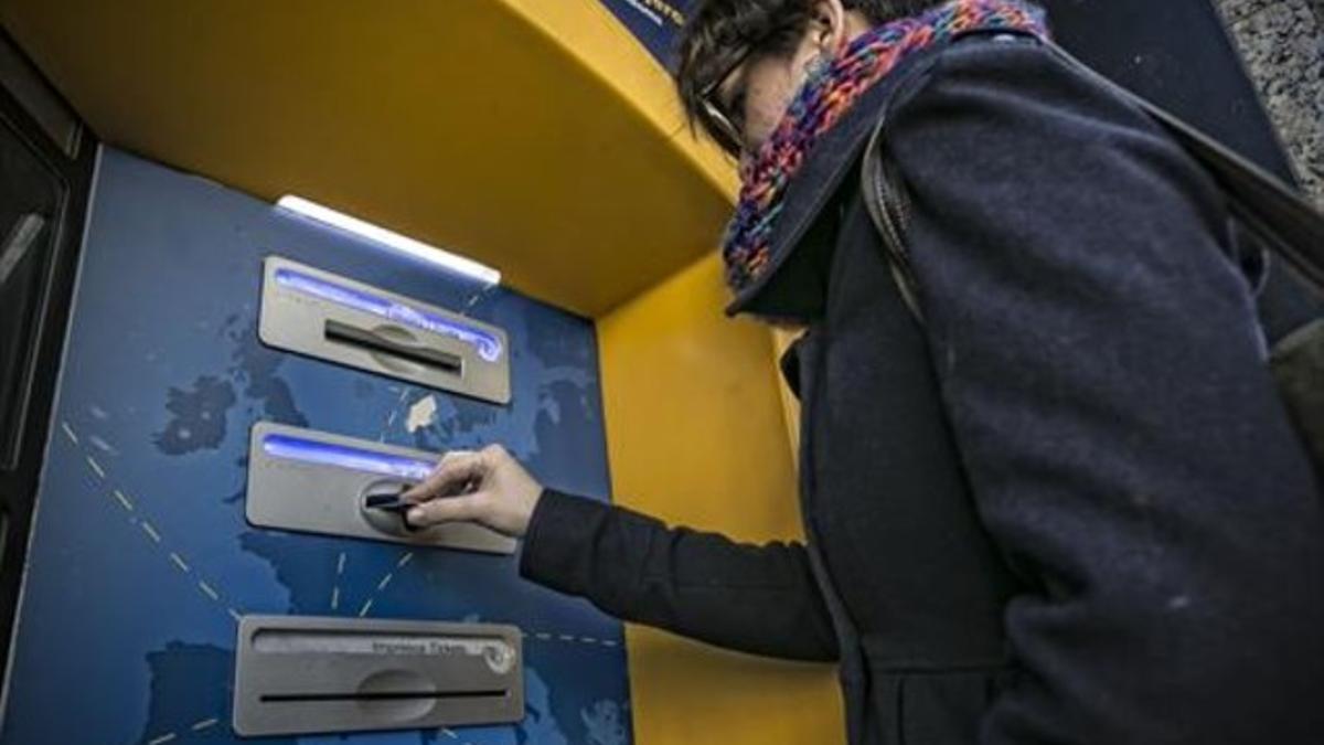 Comisiones 8Una cliente de bancaria utiliza su tarjeta en un cajero automático en una oficina de Barcelona.