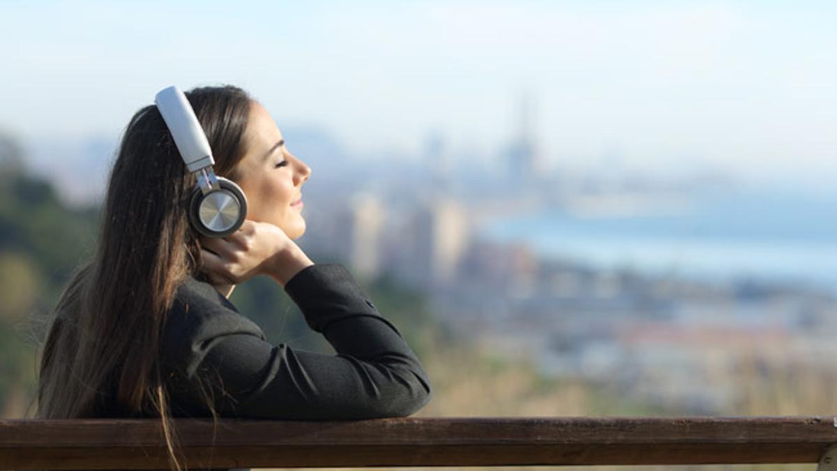 Clubhouse, la red social basada en audio que triunfa. Mujer con auriculares escuchando música.