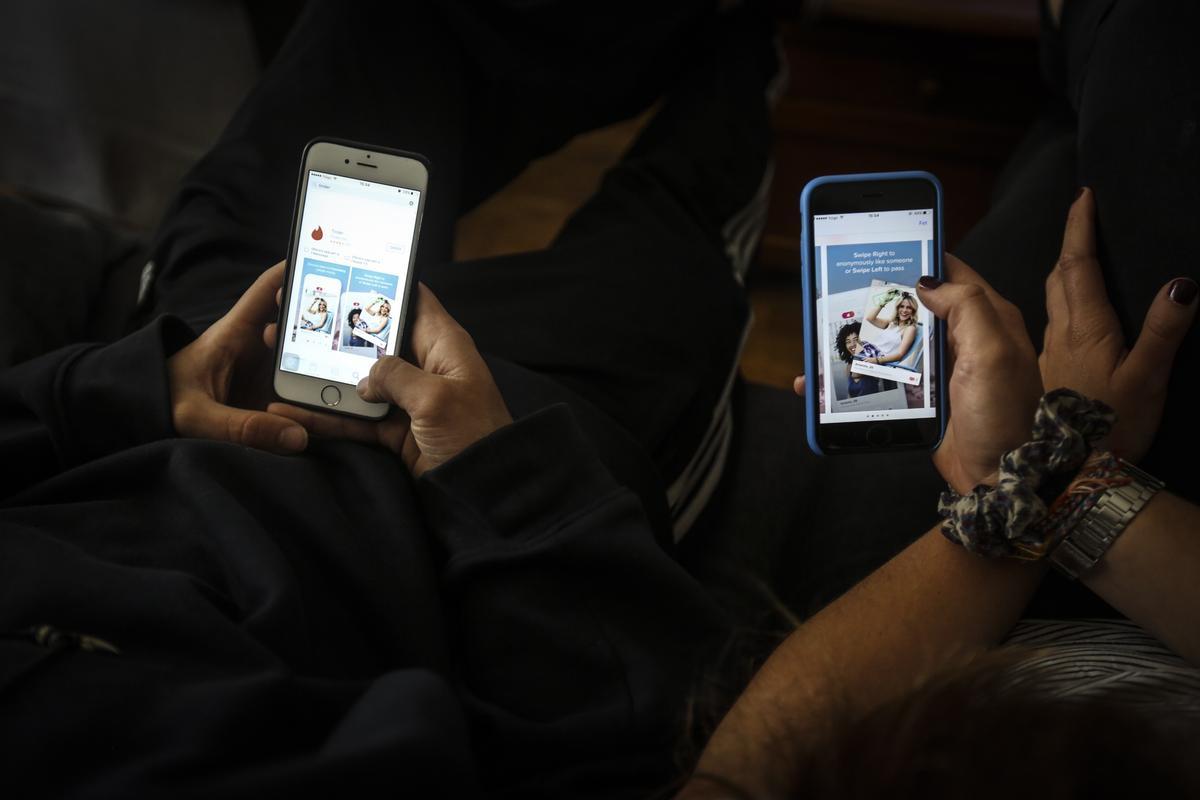 Dos jóvenes utilizando una popular aplicación para ligar desde sus teléfonos móviles.