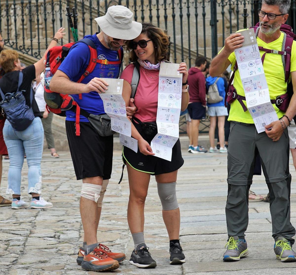 Tres peregrinos, dos de ellos con vendajes en la rodilla, muestran sus credenciales del Camino/jesús prieto