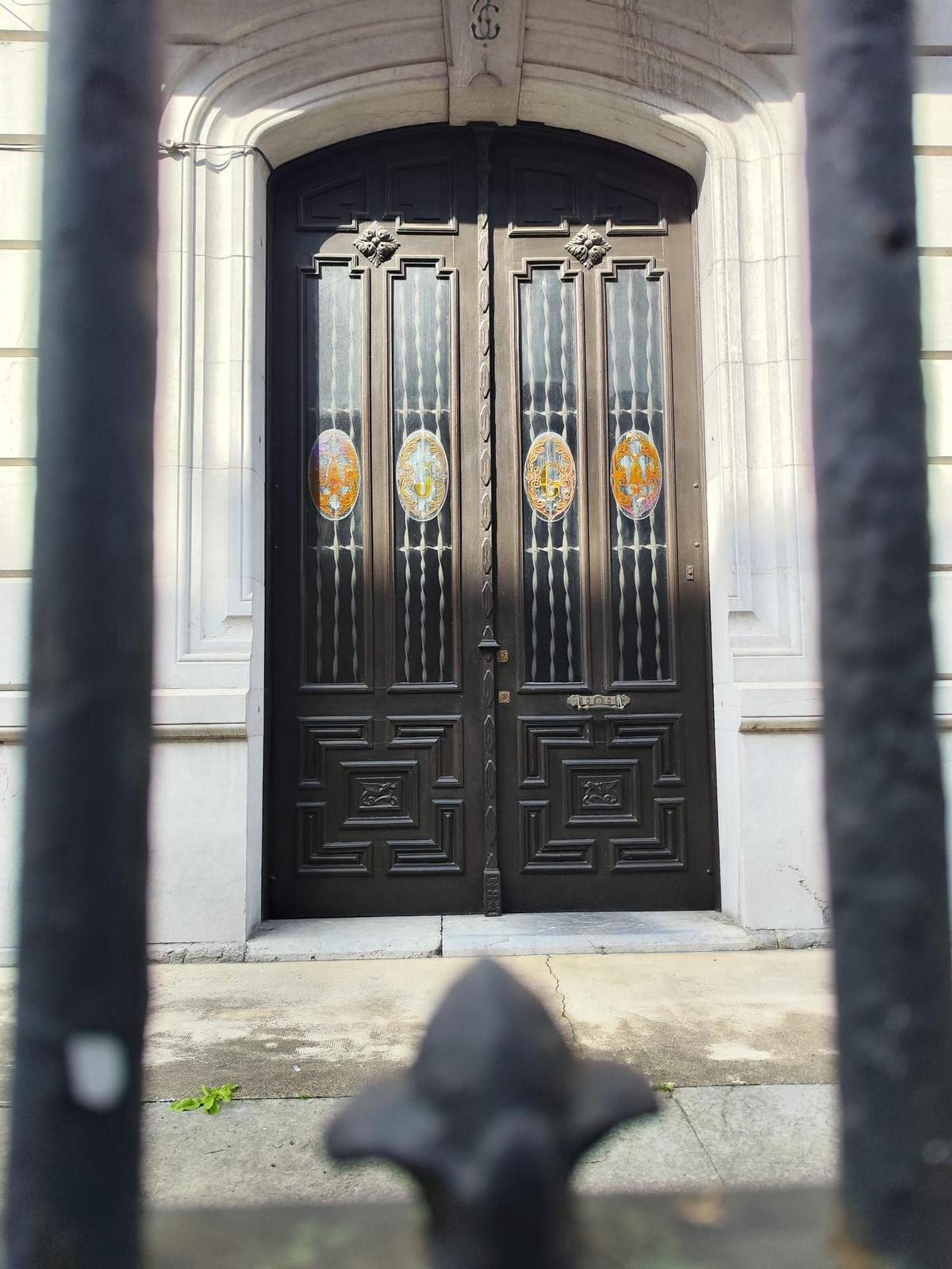 Detalle de la puerta, con las iniciales del dueño sobre llos cristales.