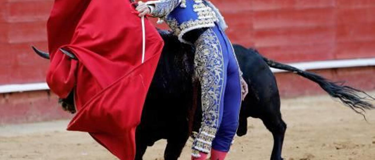 El toro engancha la muleta de López Simón en un pase cambiado por la espalda.