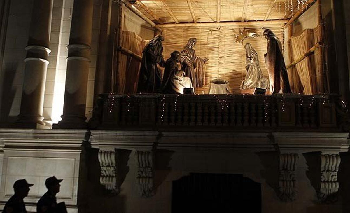 Dos agents de policia patrullen davant d’un pessebre col·locat sobre un balcó al palau de Govern al centre de Lima (Perú).