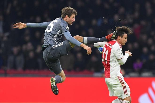 El delantero del Bayern Munich, Thomas Mueller (L), patea la espalda del defensa del Ajax, Nicolas Tagliafico, durante el partido de fútbol del Grupo E de la UEFA Champions League entre el AFC Ajax y el FC Bayern Munchen en el Johan Cruyff Arena.