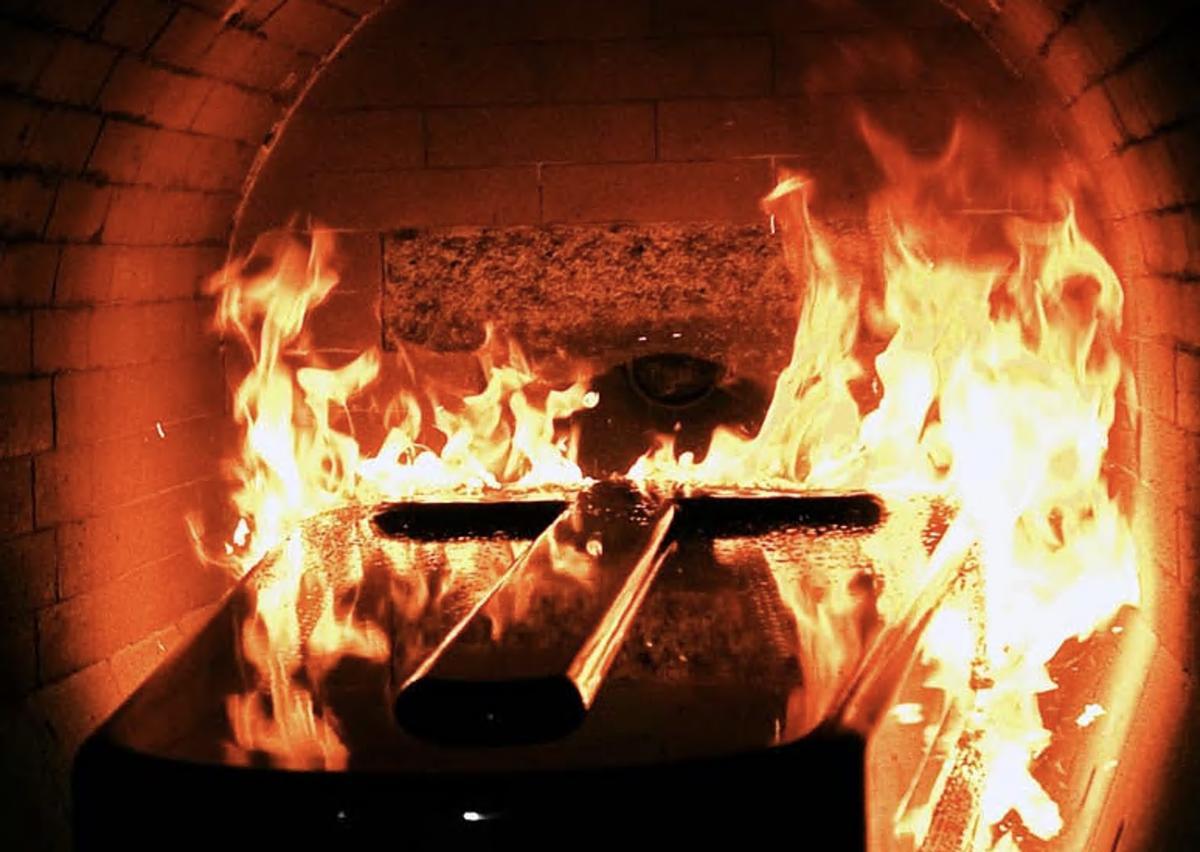 Un féretro pasando por el horno crematorio en pleno funcionamiento.