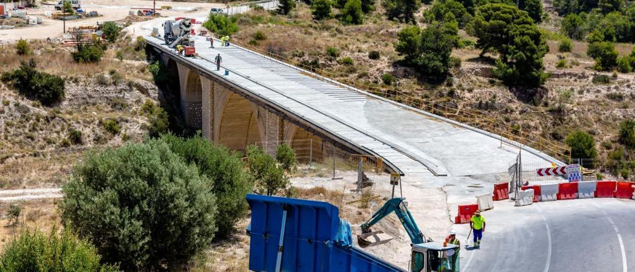 Los operarios y maquinaria, ayer, trabajando en las obras del puente de la carretera de acceso a Orxeta.