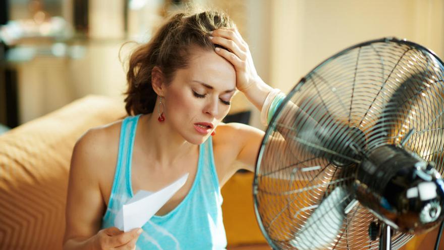 Una mujer sufre el calor frente a un ventilador.