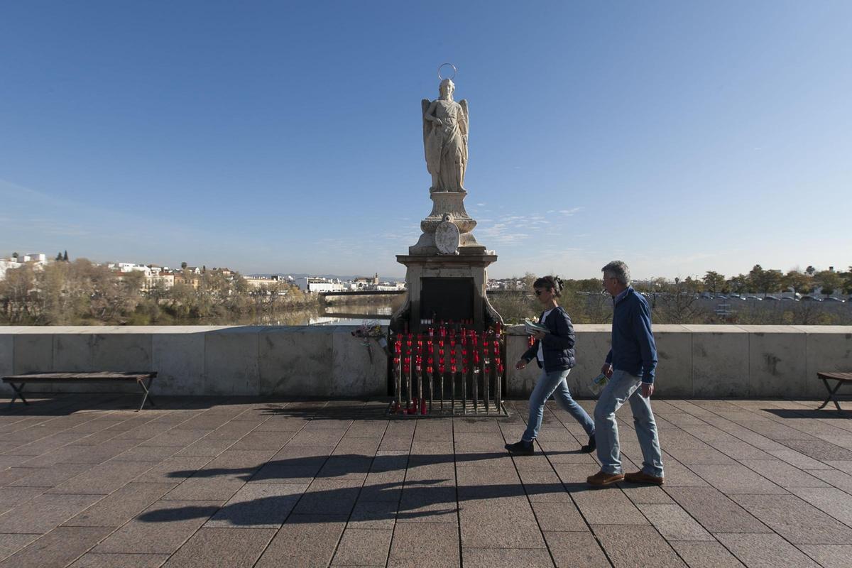 Dos personas pasan delante del San Rafael del Puente Romano, uno de los más venerados por los cordobeses.