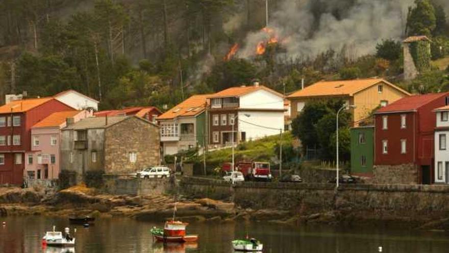 Las llamas se acercan a unas casas en el municipio de Carnota.  // Efe / Óscar Corral