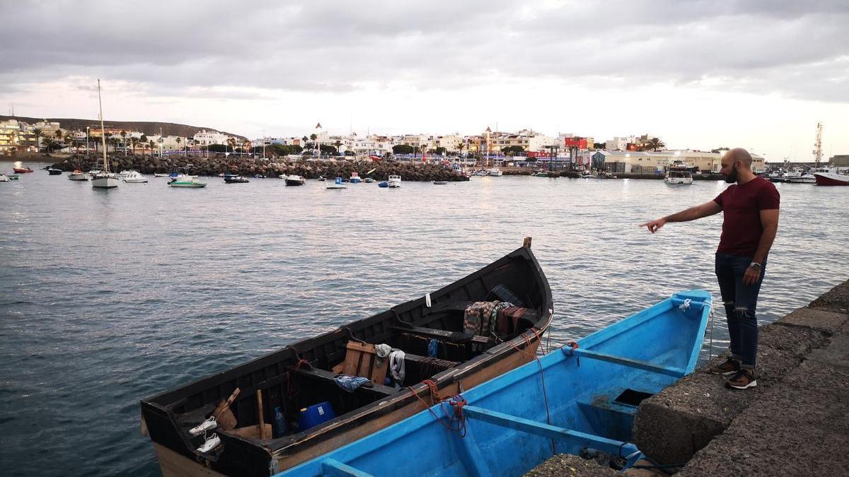 Miguel Vela, junto a los dos cayucos que flotan en el muelle de Arguineguín, el lugar de Gran Canaria donde desembarcan las pateras.